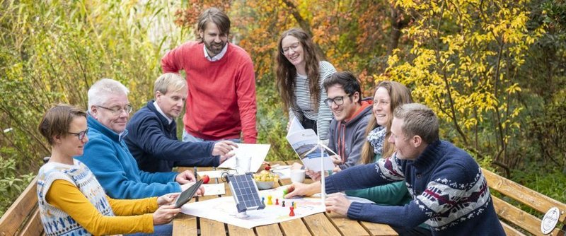 Gruppe draußen am Tisch plant und diskutiert Klimaschutz